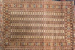 An Iranian Rug:, of Turkoman design, the beige field with four rows of quartered medallions,