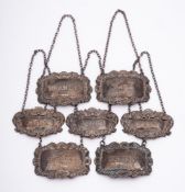 Seven assorted silver decanter labels,