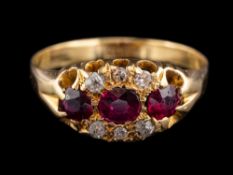An 18 carat gold ruby and diamond ring,: the three oval cut rubies with old diamonds to the side,