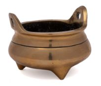 A Chinese bronze tripod censer: of squat circular form with loop handles to the rim,