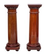 A pair of mahogany cylindrical jardiniere stands:, with square tops and canted square bases,