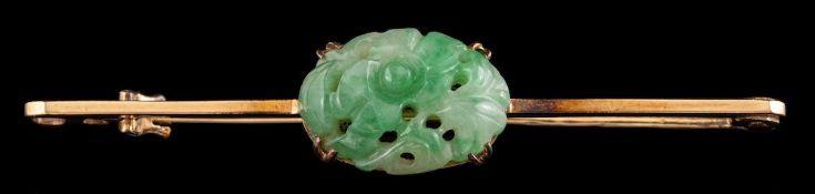 A carved jadeite brooch,: the oval carved jadeite on a bar brooch, 5.1cm wide.