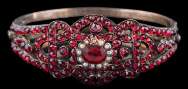 A late 19th century Russian garnet and seed pearl hinged bangle,