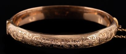 A 9 carat gold bracelet,: the hinged bracelet with engraved foliate decoration,