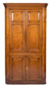 A late 18th Century oak standing corner cupboard:, with a moulded cornice and canted angles,
