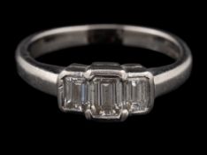 A platinum diamond three stone ring,: the central rectangular cut diamond estimated to weigh 0.