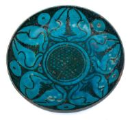 A Kashan pottery saucer dish: of shallow circular form painted in black with stylised bud motifs on