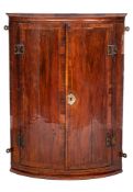 An 18th Century walnut bow-fronted hanging corner cupboard:, with a moulded cornice,