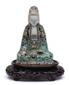 A Chinese famille verte biscuit figure of Guanyin: seated cross-legged, her face with gentle smile,