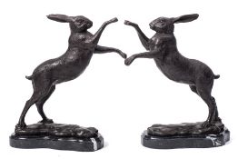 A pair of bronze fighting hares: rearing on hind legs mounted on naturalistic bases and polished