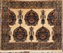A Kashmir rug:, the ivory field with indigo ogee medallions with urns of palmettes and leaves,