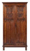 An oak wardrobe in Gothic revival taste, early 20th century,: with moulded cornice above twin doors,