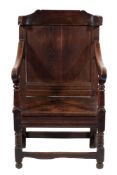 A 17th Century and later oak open armchair:, the panelled back with shaped and curved top rail,