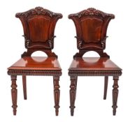 A pair of William IV carved mahogany hall chairs:,
