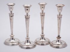 A set of four 19th Century silver plated candlesticks: with plain urn-shaped sconces on slender
