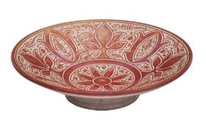 An art pottery shallow dish: of circular footed form with profuse ruby lustre decoration,