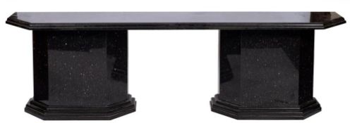 A contemporary black granite side table: the moulded chamfered top raised on end supports on
