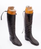 Two pairs of black leather riding boots: one with wooden trees.