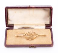 An 18ct gold bar brooch: with central swastika enclosed within a scroll frame, 7cm long, 4.