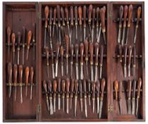 A collection of seventy ornamental woodworking tools in a mahogany wall cabinet: various makers