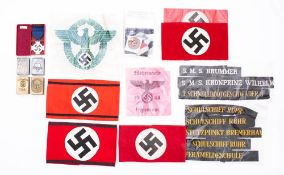 A collection of German NSDAP arm bands together with a group of hat talies and metal vesta cases.