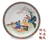 A Chinese famille rose saucer dish: enamelled with a sage and seated figure at a table in a garden,