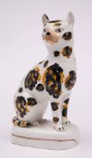A 19th century Staffordshire pottery figure of a cat: seated on its haunches,