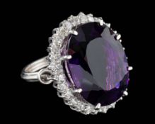 An amethyst and diamond dress ring,: the central oval cut amethyst in a claw setting,