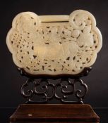 A large Chinese jade plaque in the form of a lock: carved and pierced to one side with a diety