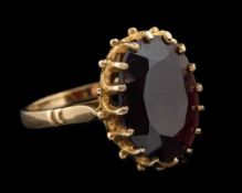 A 9 carat gold garnet ring,: the oval cut garnet in a claw setting,