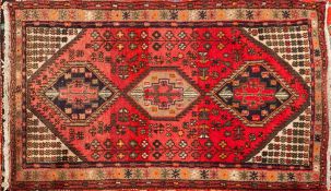 A Caucasian rug:, the rose field with triple serrated lozenge medallions,