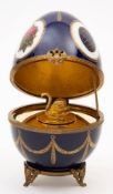 A Limoges porcelain musical egg in the Faberge style: decorated with panels depicting various eggs