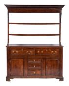 An 18th Century oak dresser:, the shelved superstructure with a moulded cornice,