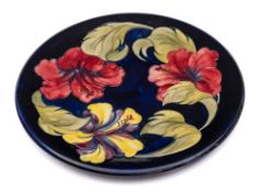 A Moorcroft pottery circular plaque: tube lined in the Hibiscus pattern in red, yellow,