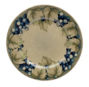 A William Moorcroft dish: painted and slip lined in the 'Grape and Leaf' pattern,