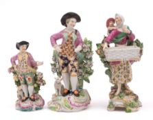 A group of three English porcelain figures: comprising a Chelsea bocage sweetmeat figure of a