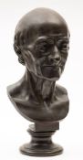 After Houdon, a bronze bust of Voltaire: raised on a bronze socle base, stamped HOUDON, 42cm high.