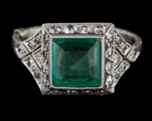 A 1920s emerald and diamond ring: the square cut emerald collet set within a surround of eight cut
