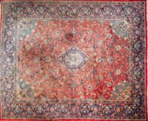 An Indo Persian carpet:, the brick red field with a central indigo cartouche pole medallion,