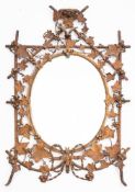 A late Victorian bronzed metal wall mirror: the oval bevelled mirror plate enclosed by a bamboo and