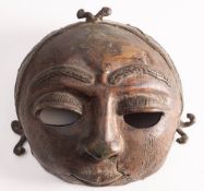 A Benin bronze mask: of traditional circular design with platted hair, 20cm high.