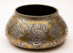 A Damascus ware brass and silver inlay bowl: of squat circular form, decorated with script, birds,