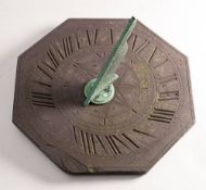 A slate sun dial, 19th century,: of octagonal outline, with bronze gnomon, indistinctly signed,