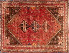 A Shiraz carpet:, the rose field with triple stepped lozenge cruciform medallions,