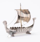 A continental white metal model of a Viking longship: set sail over carved bow and stern uprights