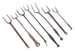 A collection of seven twin pronged toasting forks: of various designs.