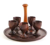 A lignum vitae circular quail's egg cruet stand: with central turned handle, 18cm diameter,