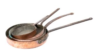 Four circular copper frying pans: of varying sizes, each with an iron handle, 19cm - 33cm diameter.