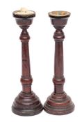 A pair of mahogany candlesticks: with brass sconces, turned stems and mound bases, 31cm high,