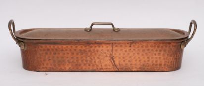 A French oval copper twin-handled fish kettle and cover: with hammered dimpled finish,